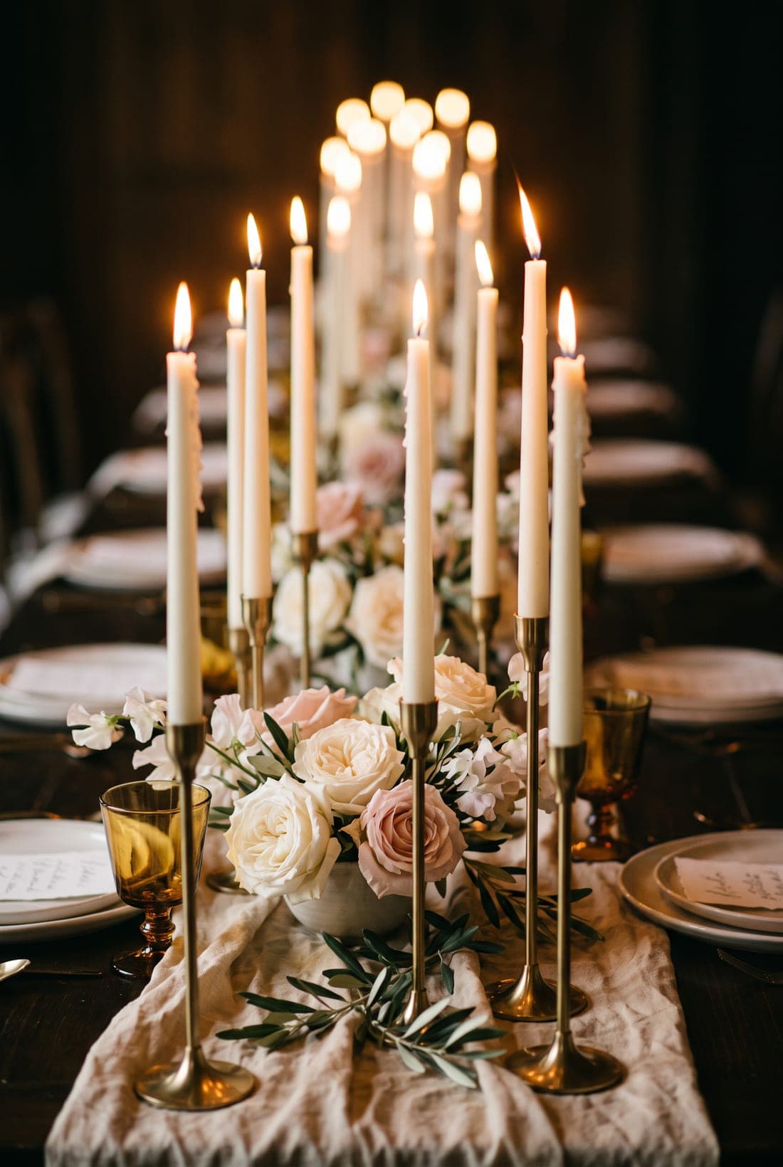 Ivory taper candles and garden roses down a candlelit dinner table