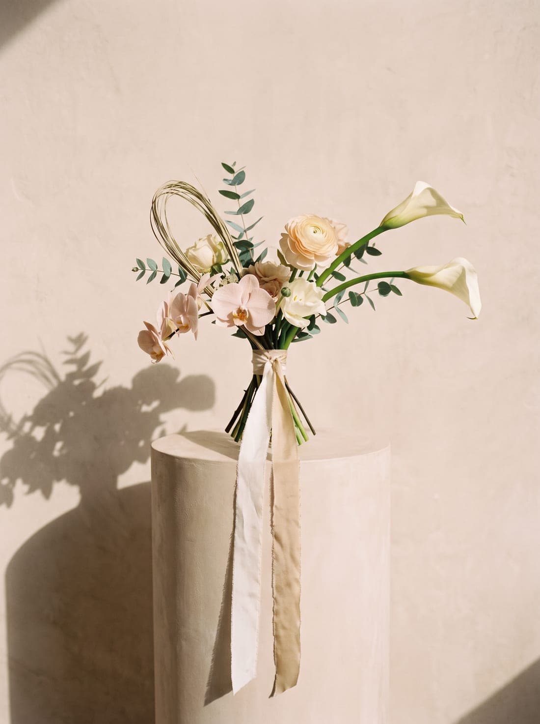 A modern, sculptural bridal bouquet with trailing silk ribbons